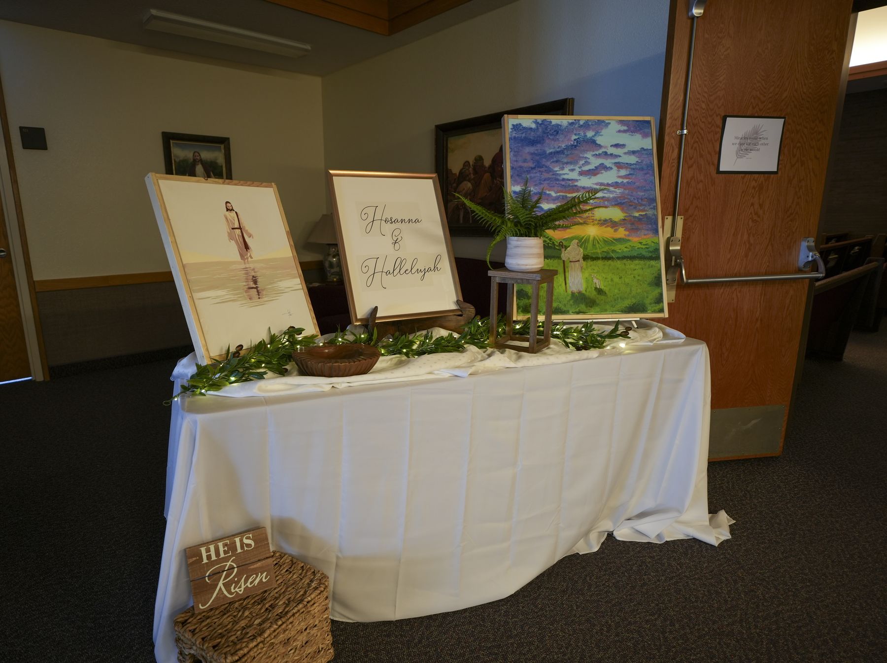 The welcome table, with paintings of Christ and a sign reading Hosanna and Hallelujah.