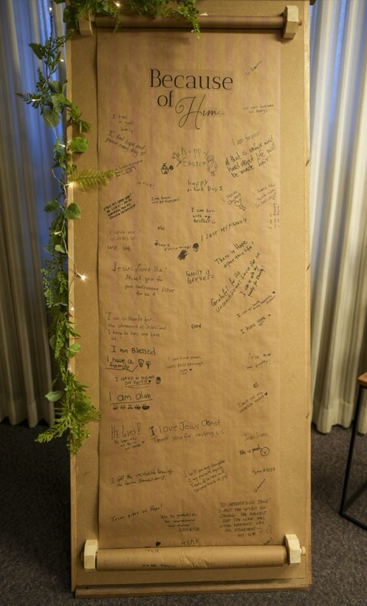 A tall paper scroll headed Because of Him, filled with notes written by guests.
